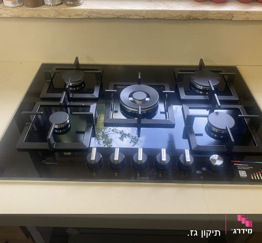 כיריים גז שחורות עם חמישה מבערים וכפתורי שליטה כסופים